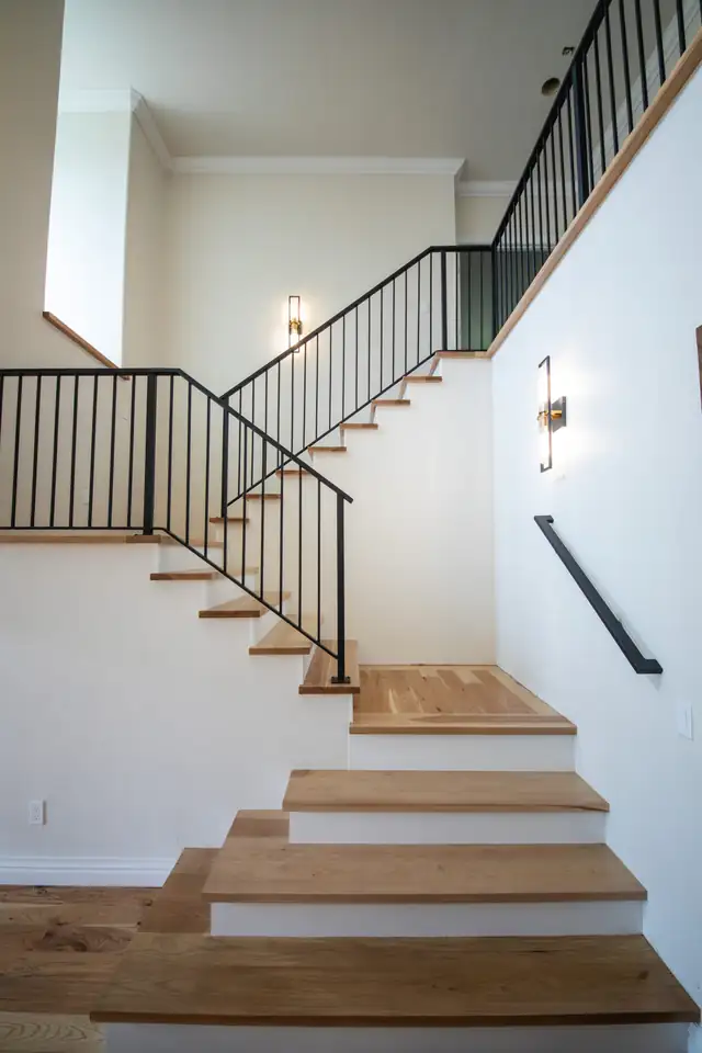 Renovated staircase with wood treads, black iron railings and white walls in the Stone Gate Lodge whole-home remodel