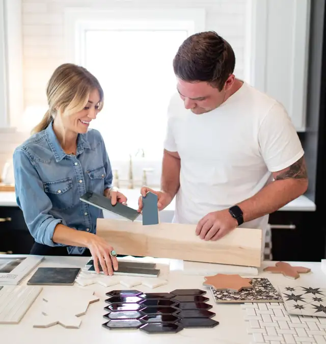 OKC Kitchen & Bath designers comparing tile samples and wood flooring planks on a kitchen counter