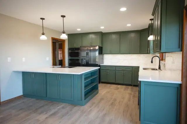 Evergreen kitchen remodel with muted green cabinets, a white quartz island and stainless steel appliances