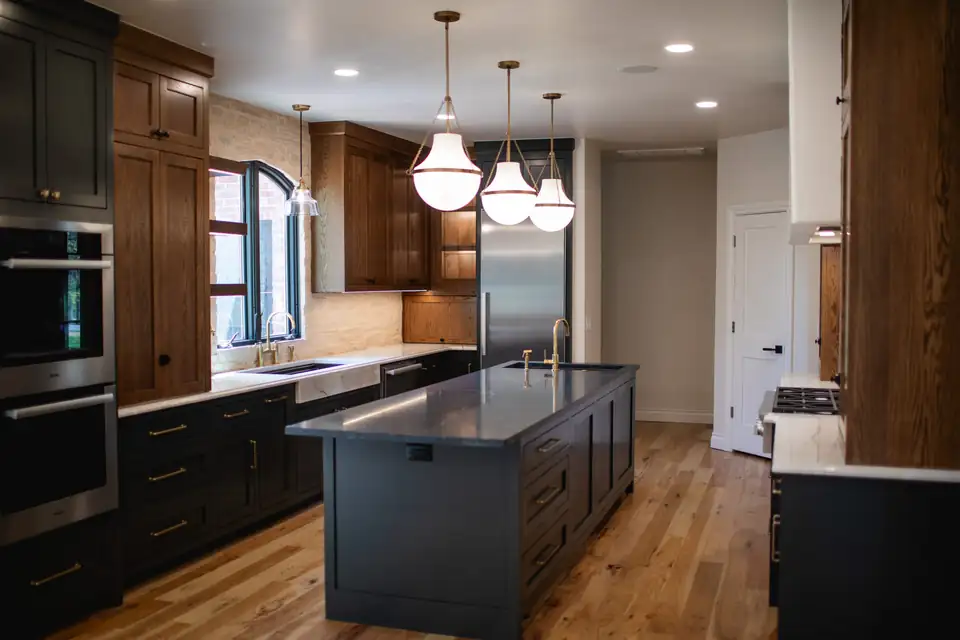 Kitchen remodeling Oklahoma City project, the Stone Gate Lodge: dark painted island, white oak cabinetry, dark stone counters and glass pendant lights