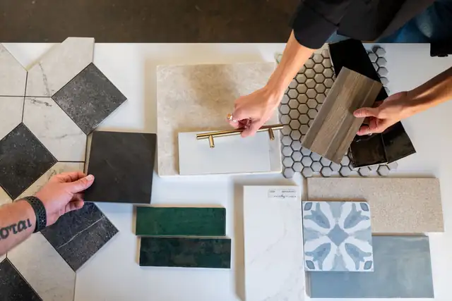 Designers arranging tile, hardware and flooring samples on a table during a selections meeting
