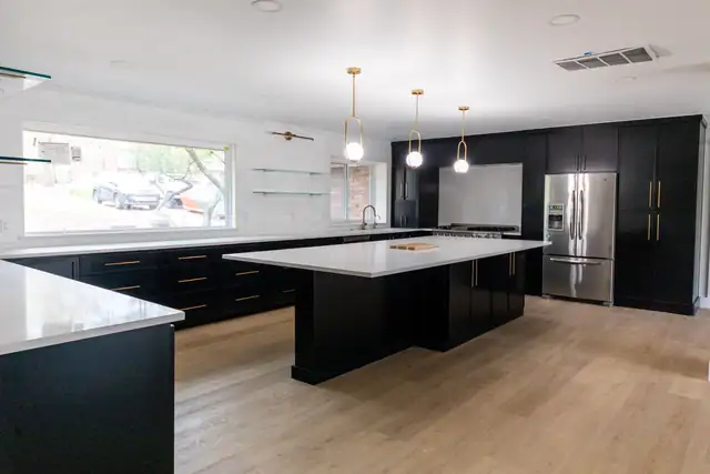 Kitchen with a large island, black cabinetry and gold pendant lighting
